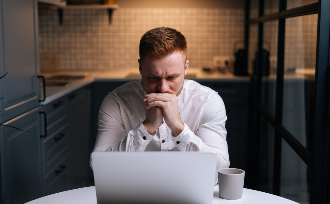 Nachdenklicher Mann im Büro vor dem Laptop, der über die Gestaltung einer Steuerberater Website nachdenkt